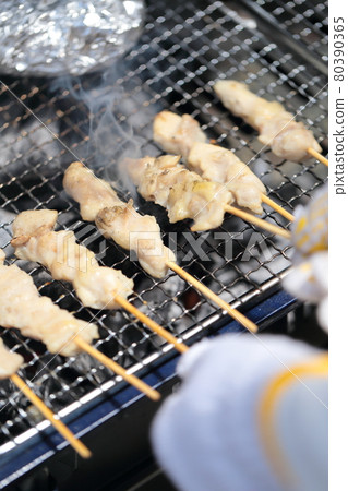 Hands of a woman cooking yakitori on a barbecue Hands of a woman cooking yakitori on a barbecue 80390365