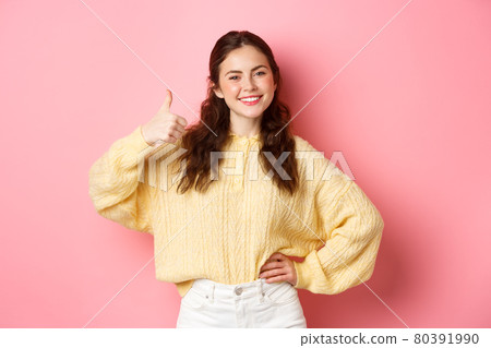 Image of confident smiling girl shows her support, makes thumbs up in approval, likes and agrees with you, praise good choice, stands against pink background Image of confident smiling girl shows her support, makes thumbs up in approval, likes and agrees with you, praise good choice, stands against pink background 80391990