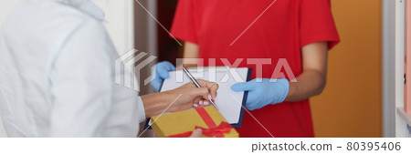 Woman courier in protective medical mask and gloves delivers parcel 80395406