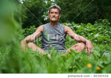 Senior man meditating in nature around the trees 80395438