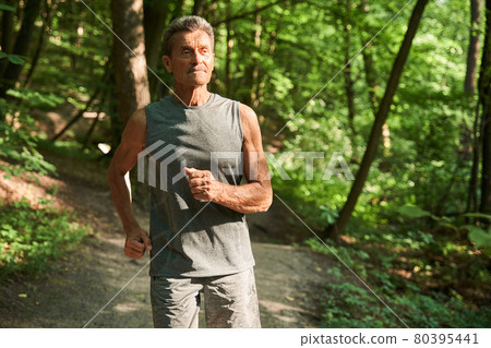 Senior male runner jogging at the park while training outdoors 80395441