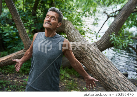 Senior man with closed eyes spread his hands and breathing summer freshness 80395470