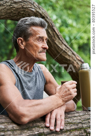 Man looking at the distance and drinking hot tea while relaxing after workout 80395527