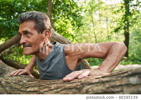 Senior fitness man training push up outside in the forest in summer Senior fitness man training push up outside in the forest in summer 80395539