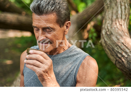 Man standing at the forest and smells aroma of the hot tea from the cup 80395542