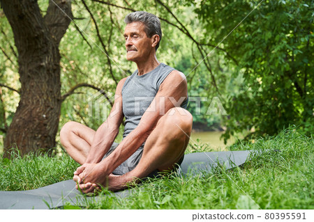 Mature man making stretching exercises at the nature at the open air Mature man making stretching exercises at the nature at the open air 80395591
