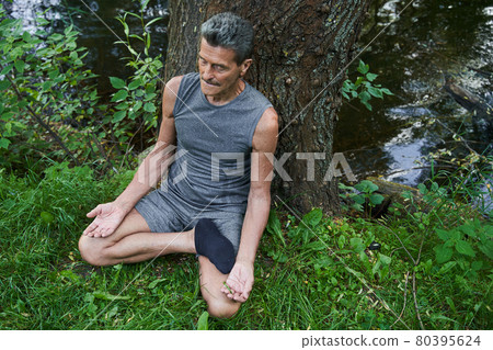 Pensioner working out and sitting in lotus pose while feeling relaxed 80395624