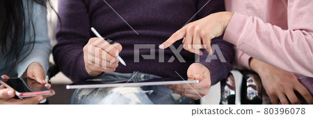 Employees point to tablet screen while discussing hot topics 80396078
