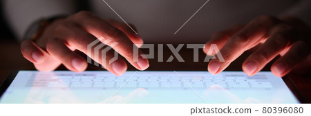 Female fingers are typing on tablet screen at night 80396080