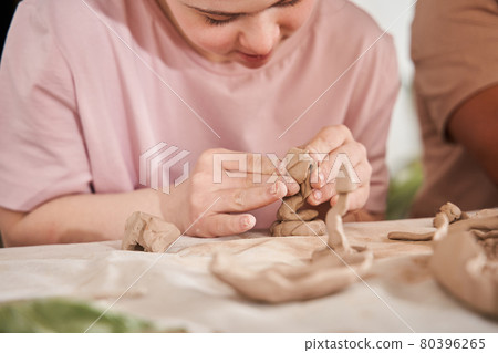Woman with special needs working with clay in ceramic studio during the pottery workshop Woman with special needs working with clay in ceramic studio during the pottery workshop 80396265