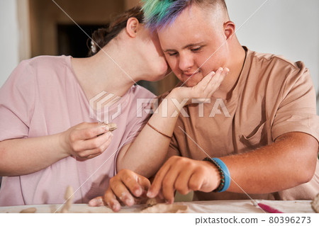 Girl with down syndrome kissing with tenderness her boyfriend after the making plates 80396273