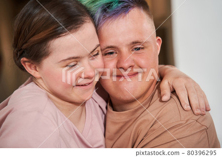 Boy with special needs embracing tight his girlfriend and looking at the camera 80396295