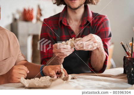 Craftsman in apron teaching young people with special needs to make a plates Craftsman in apron teaching young people with special needs to make a plates 80396304