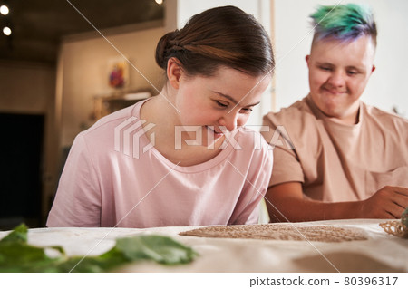 Couple with special needs looking into the pattern at the clay for future plate 80396317