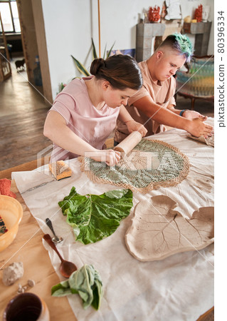 Girl with down syndrome using rolling pan to imprint ornament at the clay Girl with down syndrome using rolling pan to imprint ornament at the clay 80396334