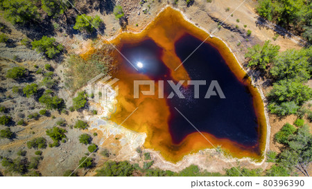Acidic red lake in place of abandoned open pit copper mine near Kinousa, Cyprus, aerial view directly above 80396390