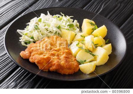 Fried pork cutlet breaded served with potatoes and cabbage salad close-up in a plate. horizontal Fried pork cutlet breaded served with potatoes and cabbage salad close-up in a plate. horizontal 80396800