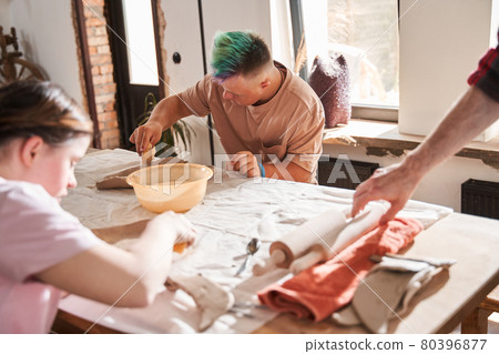 Boy with colored hair making plate from the clay at the table 80396877