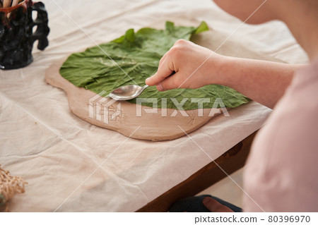 Girl holding spoon and touching to the fresh leaf laying at the clay 80396970