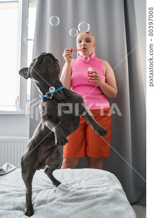 Woman standing near the bed and blowing bubbles with joy Woman standing near the bed and blowing bubbles with joy 80397008