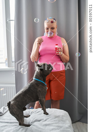 French bulldog having fun with bubbles while his female owner blowing it from soap water French bulldog having fun with bubbles while his female owner blowing it from soap water 80397011