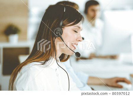 Asian woman working at customer service office. Business concept. Group of diverse operators at work in sunny call center. Asian woman working at customer service office. Business concept. Group of diverse operators at work in sunny call center. 80397012