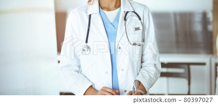Unknown woman-doctor communicating with female patient in sunny clinic. Physician checks medical history record and exam results, close-up Unknown woman-doctor communicating with female patient in sunny clinic. Physician checks medical history record and exam results, close-up 80397027