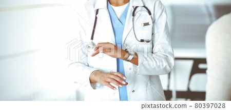Unknown woman-doctor communicating with female patient in sunny clinic. Physician checks medical history record and exam results, close-up 80397028