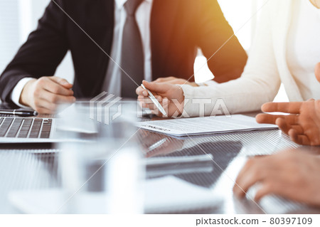 Business people discussing contract while working together in sunny modern office. Unknown businessman and woman with colleagues or lawyers at meeting 80397109