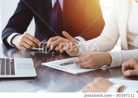 Business people discussing contract while working together in sunny modern office. Unknown businessman and woman with colleagues or lawyers at meeting 80397112
