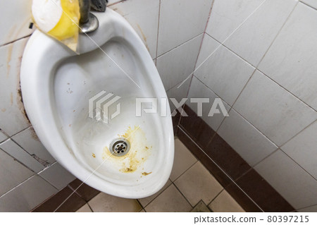 Dirty and smelly urinal bowl with limescale stain deposits 80397215