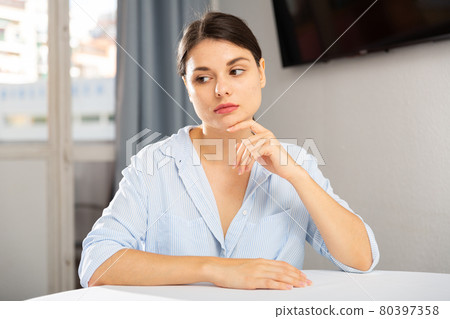 Upset young woman sitting at table 80397358