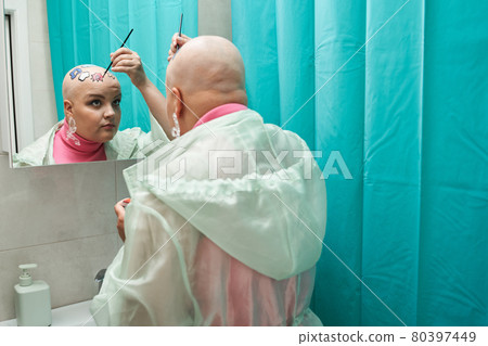 Woman holding brush and applying paints at her head while creating new look 80397449