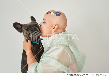 Woman with creative pattern at her head kissing at the muzzle her lovely french bulldog 80397467