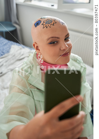 Woman with creative patterns at her head looking at her smartphone and having vide call 80397471