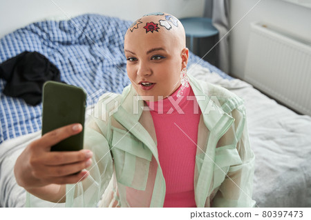 Woman with creative patterns at her head looking at her smartphone and having vide call 80397473