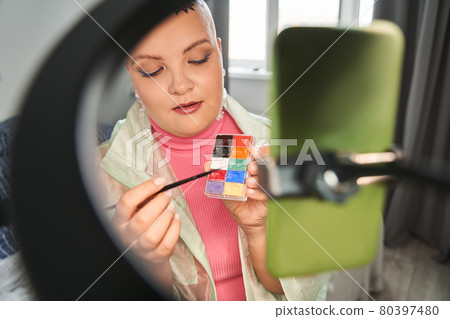 Blogger talking to camera and showing palette while recording blog about makeup Blogger talking to camera and showing palette while recording blog about makeup 80397480