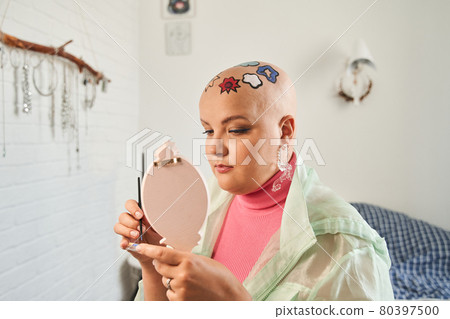 Female blogger looking at her reflection at the hand mirror while making online tutorial 80397500