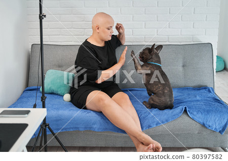 Female owner sitting at sofa and preparing to giving a treat to her french bulldog Female owner sitting at sofa and preparing to giving a treat to her french bulldog 80397582
