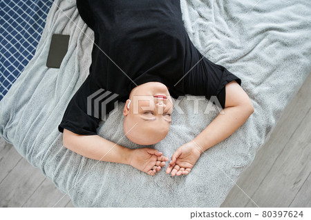 Woman in earphones laying at the bed and listening music while spending weekend at home 80397624