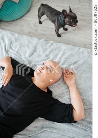 Woman in earphones laying at the bed and listening music while spending weekend at home 80397628