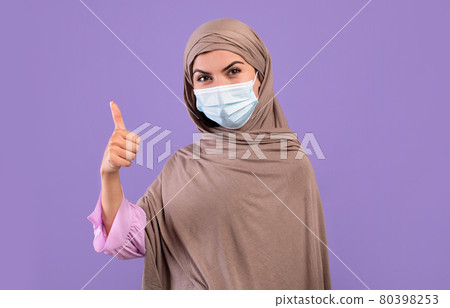 Protection against disease. Armenian woman in hijab wearing medical protective face mask, showing thumb up 80398253