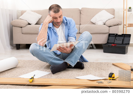 Puzzled Man Reading Furniture Assembly Manual Installing Shelf At Home Puzzled Man Reading Furniture Assembly Manual Installing Shelf At Home 80398270