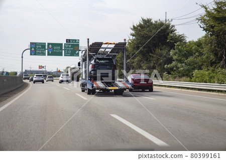 A vehicle transporting automobiles on a road 80399161