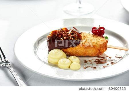 Chicken Kiev with mashed potatoes and a sprig of red currants on a bright plate, white background copy Space, the original supply of Kiev cutlets 80400513