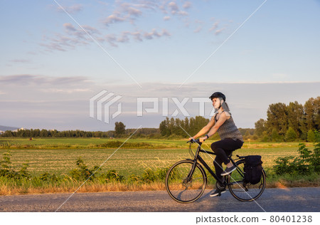 Adventurous White Cacasusian Woman riding a bicycle on a road. 80401238