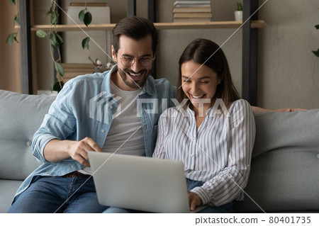 Laughing couple enjoy funny internet content while sit on sofa Laughing couple enjoy funny internet content while sit on sofa 80401735