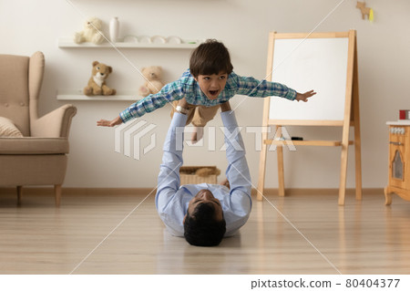Loving Indian father lifting excited son pretending flying on floor Loving Indian father lifting excited son pretending flying on floor 80404377