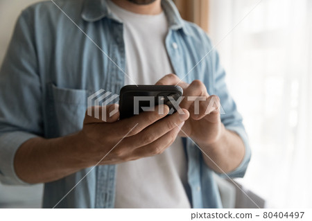 Closeup view male standing indoor holding in hands cellphone Closeup view male standing indoor holding in hands cellphone 80404497
