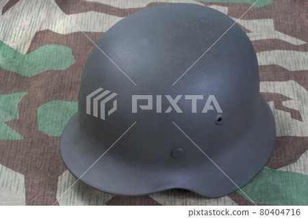 German Nazi Army steel helmet World War II period (1933-1945) on camouflaged background German Nazi Army steel helmet World War II period (1933-1945) on camouflaged background 80404716